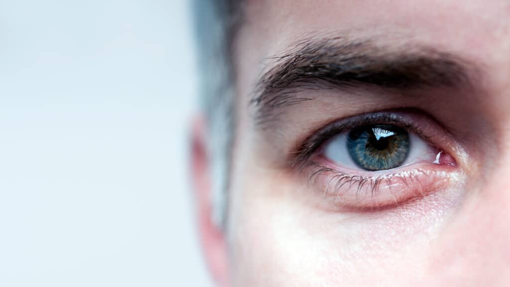 Man's teary eye, with potential vision impairment from Xiidra eye drops