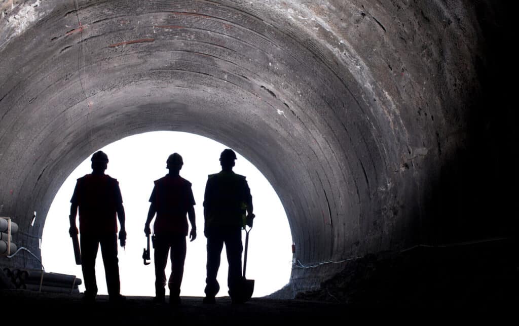Construction workers walking through a tunnel.