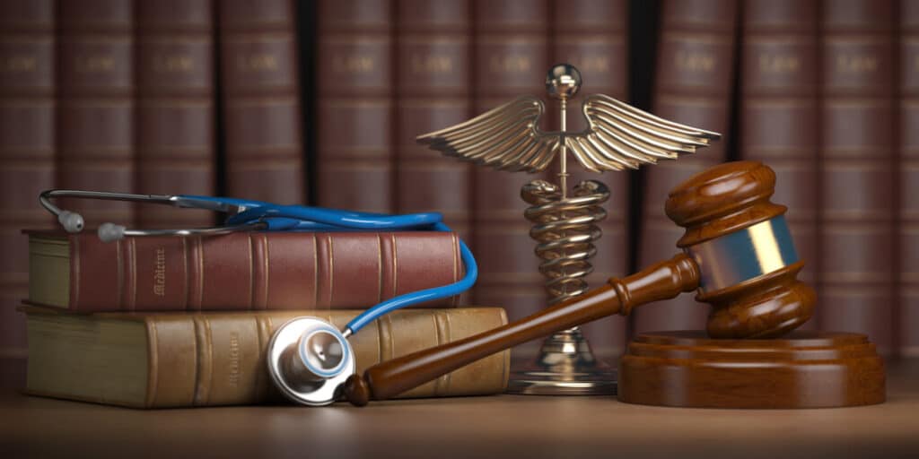 Gavel, stethoscope and caduceus sign on books background