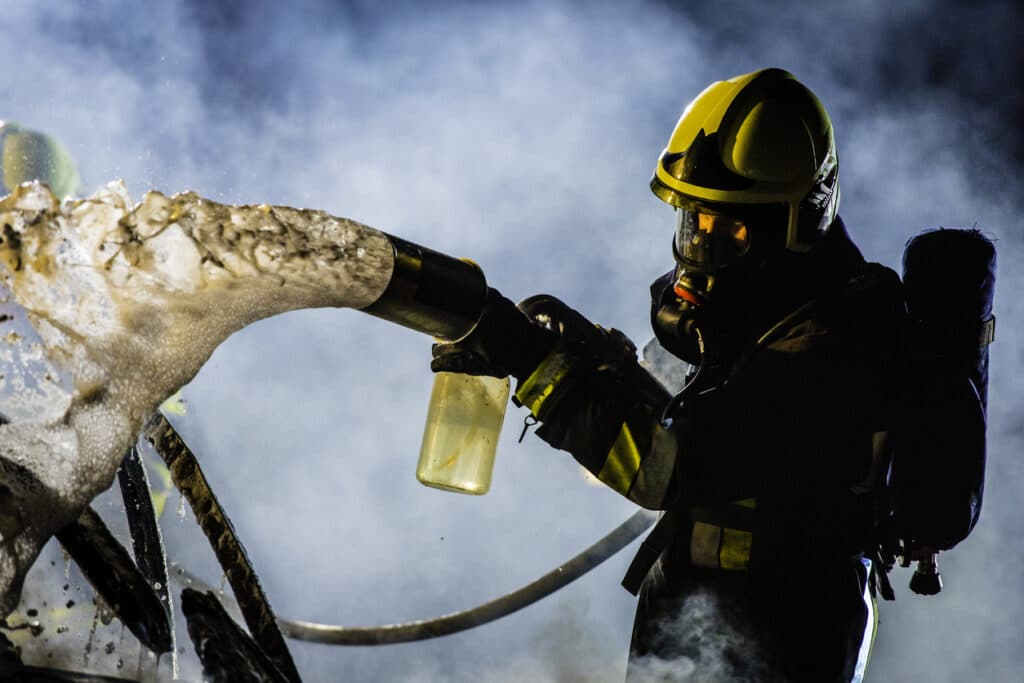 Fireman extinguishing a burning car with foam
