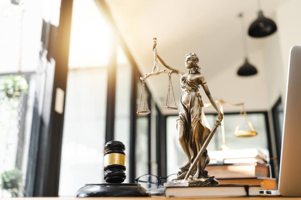 Gavel and scales of justice statue on a desk.