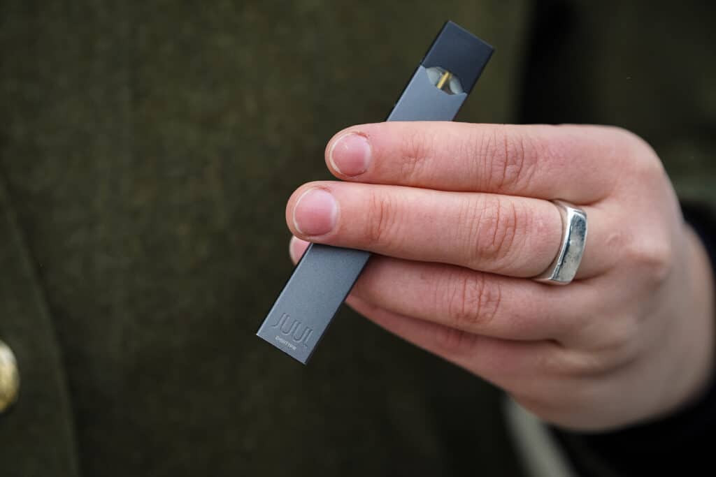 Woman holding a Juul e-cigarette.